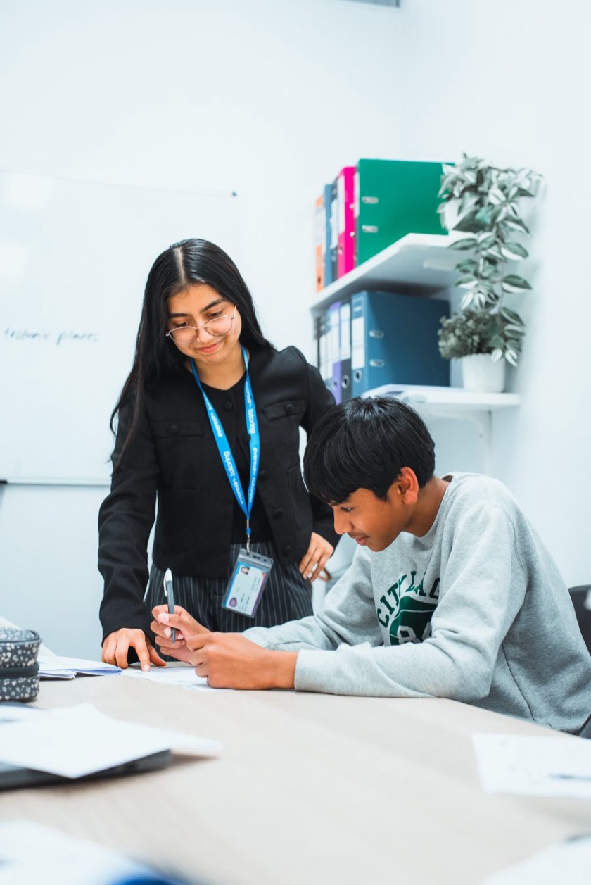 An Everest tutor helping a student with written work during an English class